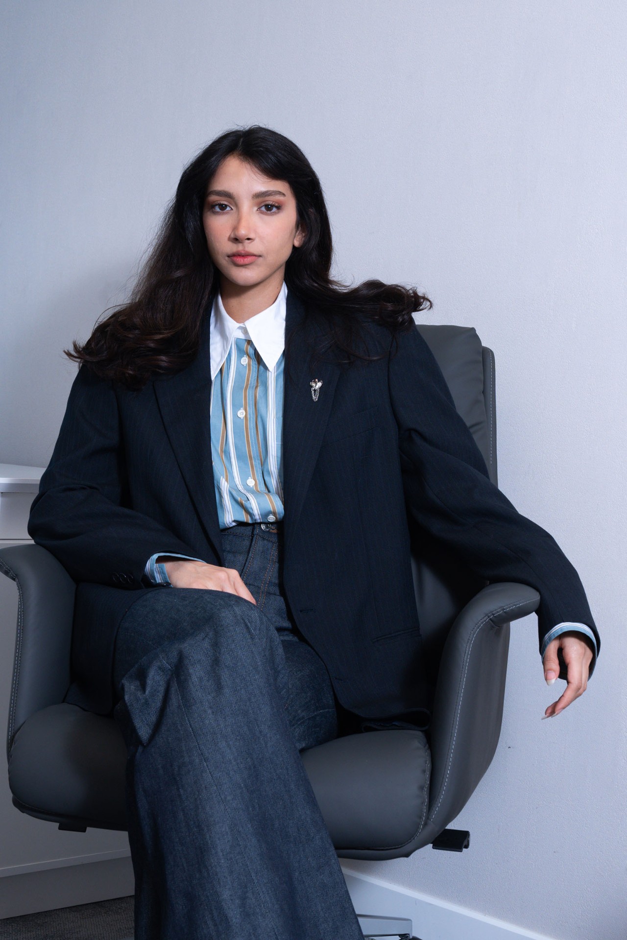Editorial portrait in oversized blazer on chair