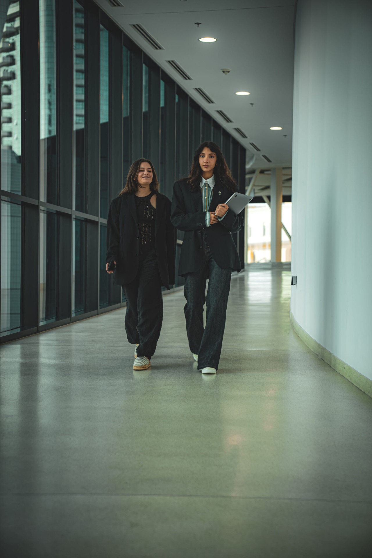 Two women walking in modern corridor